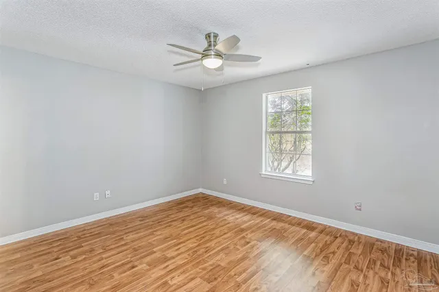a view of empty room with wooden floor and fan