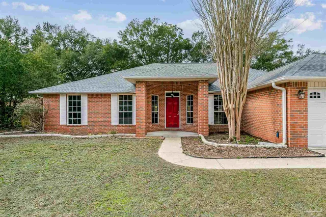 a front view of house with yard and trees in the background