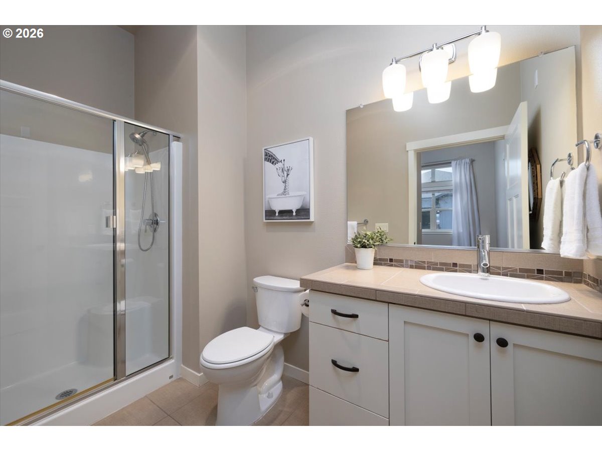 13895 Southwest Meridian Street, Unit 412 Beaverton, OR 97005 - Photo 19 of 38 a bathroom with a toilet a sink a mirror a vanity and shower