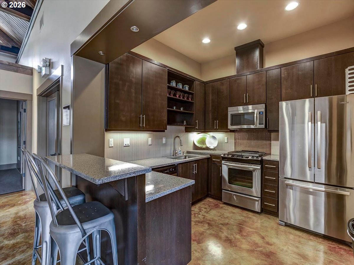 13895 Southwest Meridian Street, Unit 412 Beaverton, OR 97005 - Photo 31 of 38 a kitchen with stainless steel appliances granite countertop a sink a stove a refrigerator cabinets and chairs