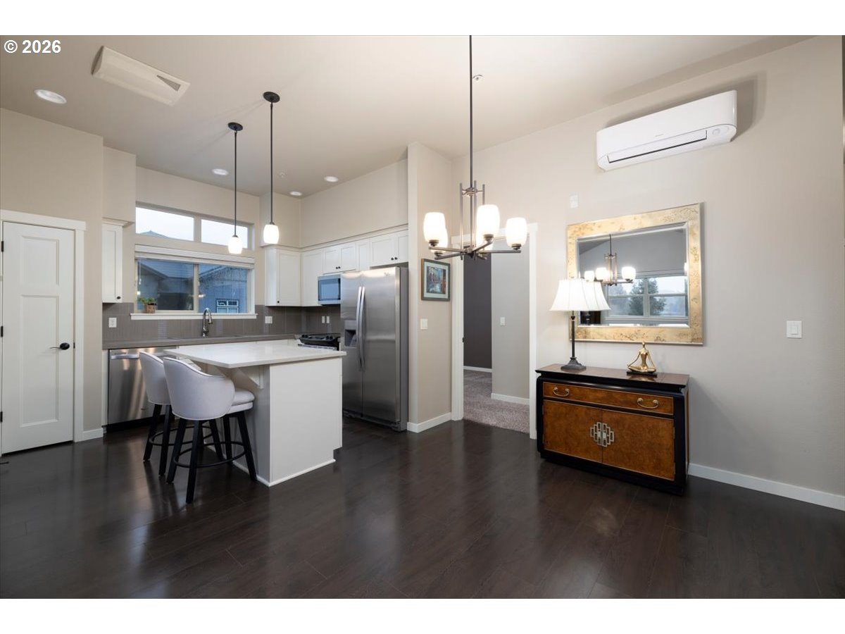 13895 Southwest Meridian Street, Unit 412 Beaverton, OR 97005 - Photo 9 of 38 a kitchen with stainless steel appliances kitchen island granite countertop a refrigerator a stove a sink and a dining table with wooden floor