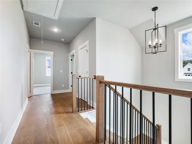 a view of a hallway with wooden floor and chandelier