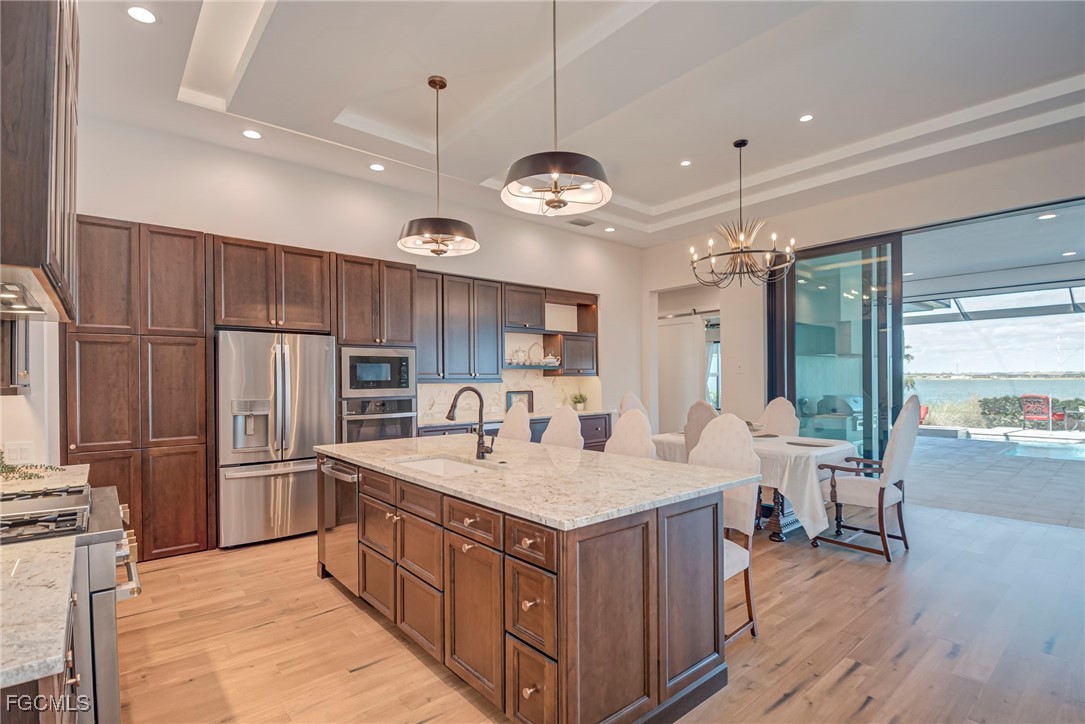 43362 Waterside Trail Punta Gorda, FL 33982 - Photo 11 of 50 a kitchen with stainless steel appliances granite countertop a kitchen island a stove a refrigerator a oven and a table with wooden floor