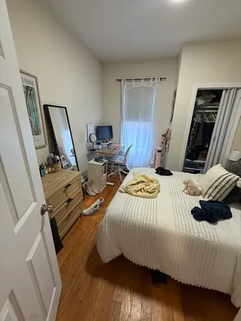 a bedroom with a bed a rug and wooden floor