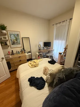 a bedroom with a bed a couch and a flat tv screen on the dresser