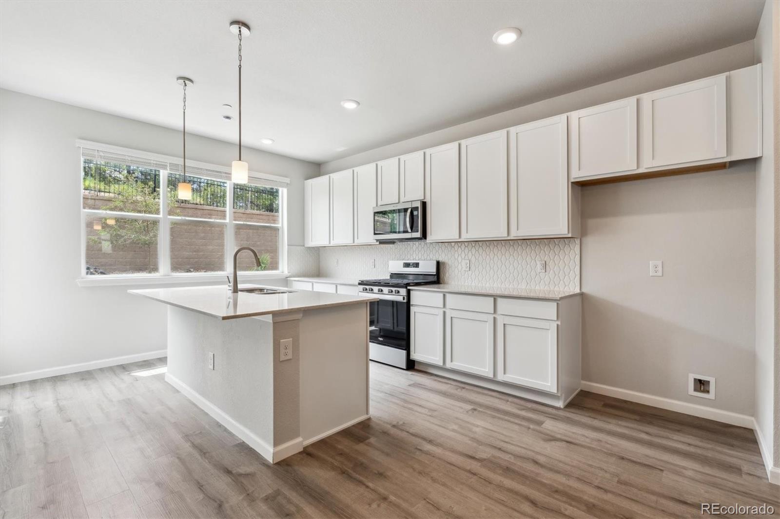 465 Interlocken Boulevard, Unit 101 Broomfield, CO 80021 - Photo 3 of 17 a kitchen with stainless steel appliances granite countertop a stove a sink and white cabinets with wooden floors