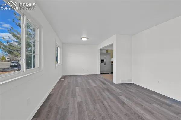 a view of empty room with wooden floor and fan