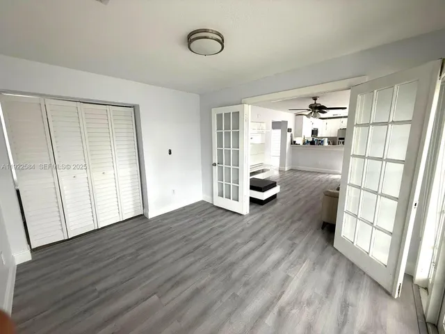 a view of empty room with wooden floor and fan