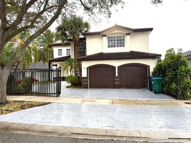 a front view of a house with a garden and tree