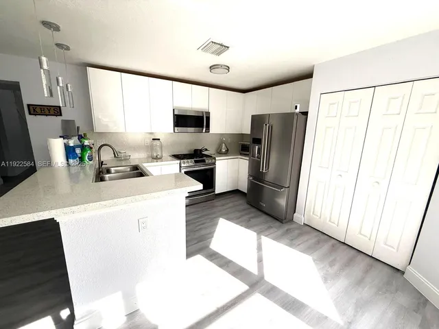 a kitchen with a refrigerator a stove a microwave a sink dishwasher and wooden cabinets