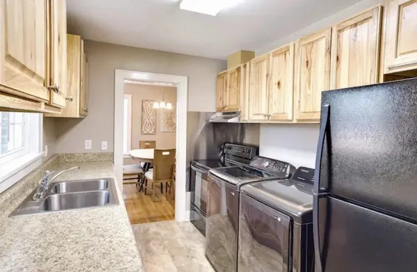 a kitchen with stainless steel appliances granite countertop a refrigerator a stove and a sink with large window