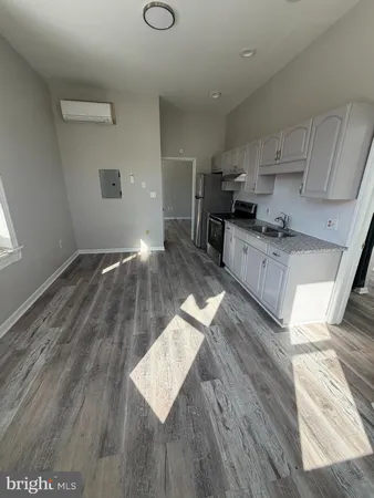 a kitchen with granite countertop a stove top oven a sink and white cabinets with wooden floor