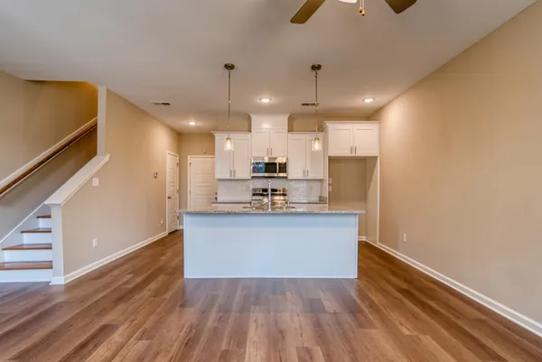 an empty room with wooden floor chandelier fan and windows