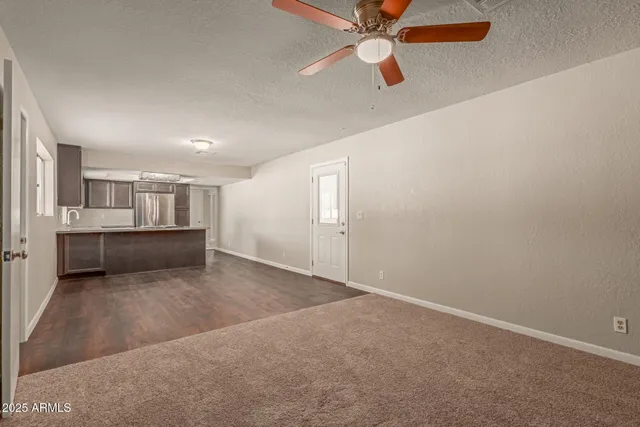 an empty room with a kitchen and a ceiling fan