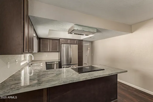 a kitchen with stainless steel appliances granite countertop a sink and a refrigerator