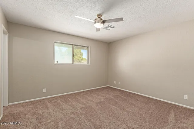 an empty room with windows and fan