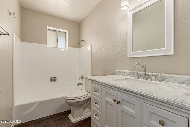 a bathroom with a granite countertop toilet a sink and a mirror