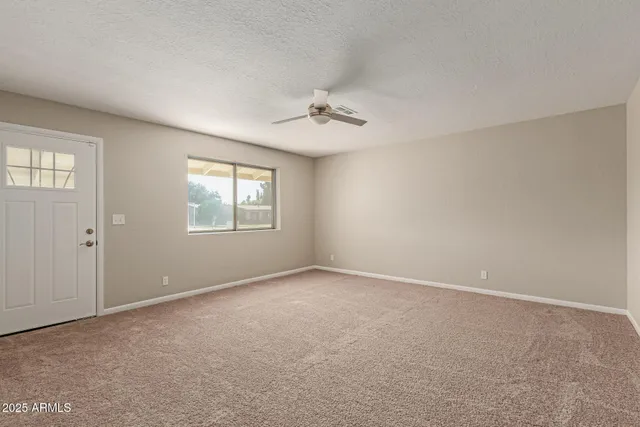 an empty room with windows and ceiling fan