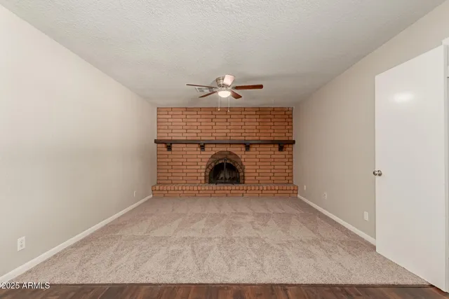 a view of an empty room with a fireplace and a fan