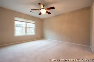 an empty room with ceiling fan and windows