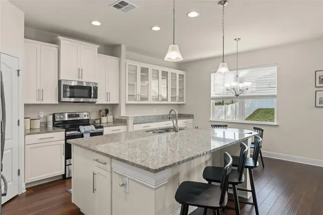 a kitchen with granite countertop a sink a counter top space cabinets and stainless steel appliances