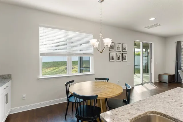 a kitchen with stainless steel appliances granite countertop a stove top oven a sink a dining table and chairs