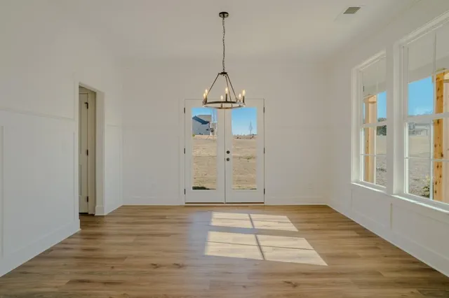 a view of an empty room with wooden floor and fan