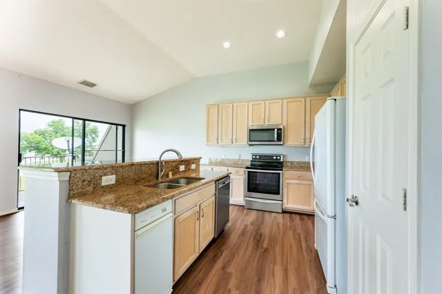 a kitchen with granite countertop a stove a sink and wooden floor