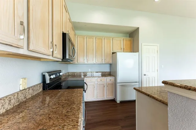 a kitchen with stainless steel appliances granite countertop a refrigerator a stove and a wooden floors