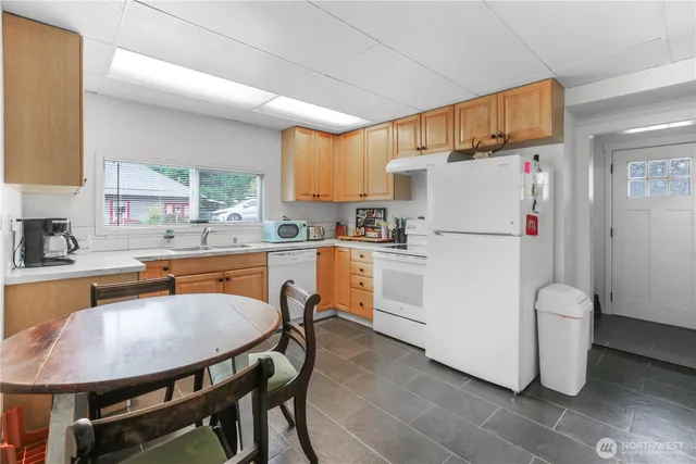 a kitchen with refrigerator a stove a sink and white cabinets