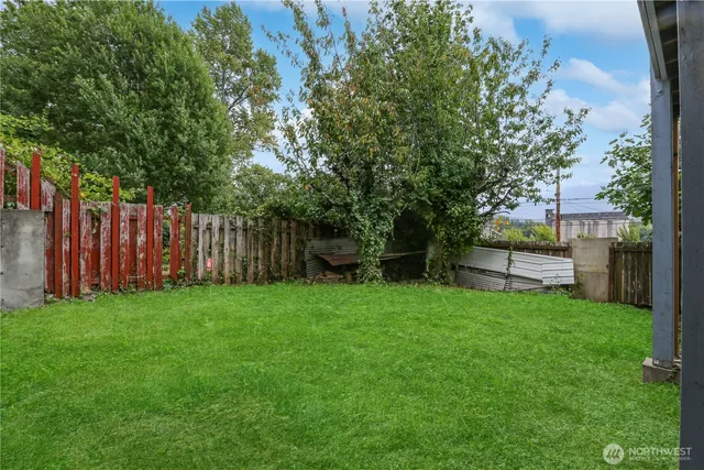 a view of a backyard with wooden fence and large trees