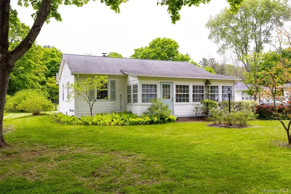 a view of a house with a big yard potted plants and large tree