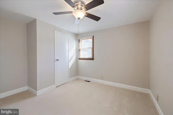 an empty room with a window and a fan