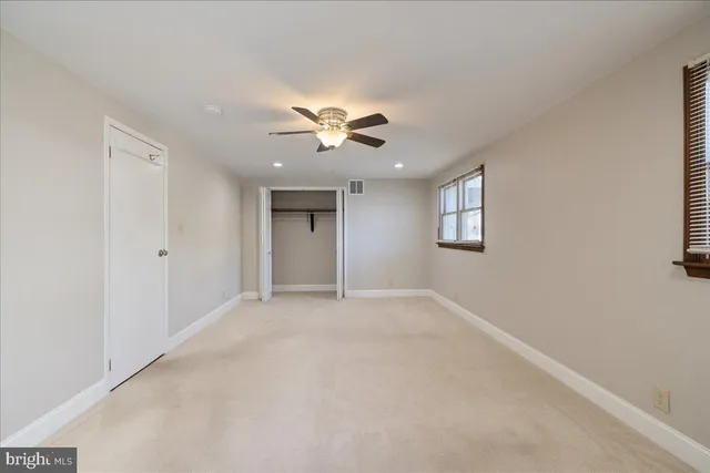 an empty room with chandelier fan and windows