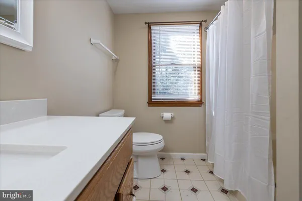 a bathroom with a granite countertop sink a toilet and a window