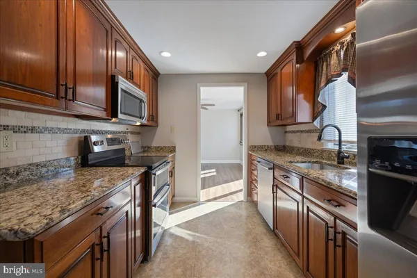 a kitchen with stainless steel appliances granite countertop a stove top oven a sink dishwasher a microwave oven and a refrigerator