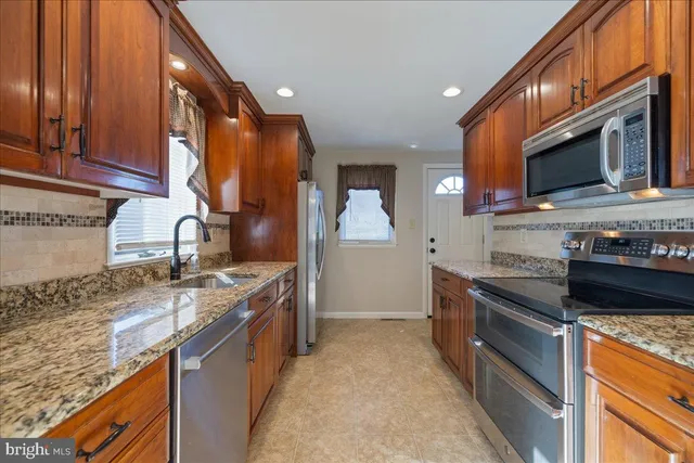 a kitchen with stainless steel appliances granite countertop a stove a sink and a microwave