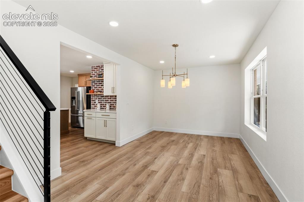 11665 Greentree Road Colorado Springs, CO 80908 - Photo 5 of 43 Unfurnished dining area with stairway, a chandelier, light wood-type flooring, and recessed lighting