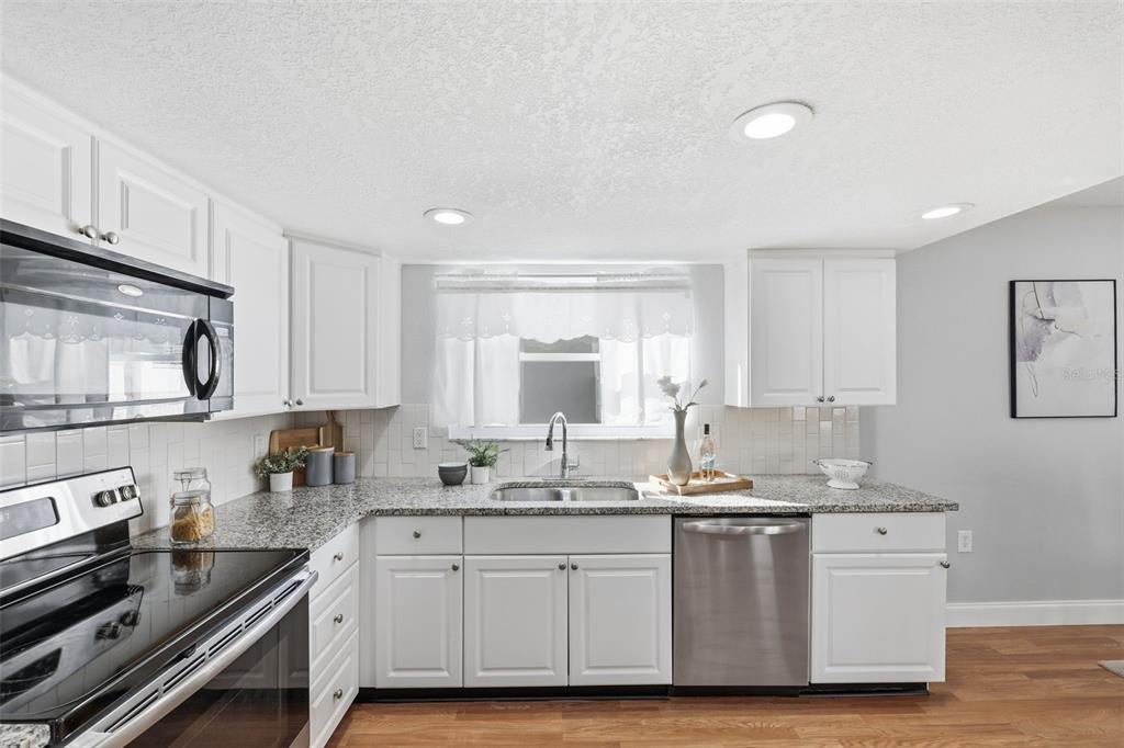 8233 Redfield Drive Port Richey, FL 34668 - Photo 17 of 36 a kitchen with stainless steel appliances granite countertop a stove a sink and white cabinets