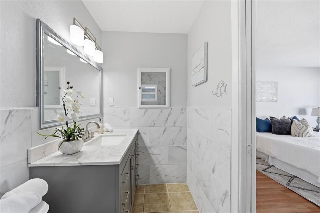 8233 Redfield Drive Port Richey, FL 34668 - Photo 25 of 36 a bathroom with a granite countertop sink a mirror and a shower