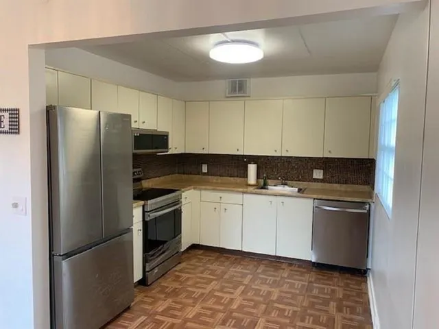 a kitchen with stainless steel appliances granite countertop a refrigerator a sink and white cabinets
