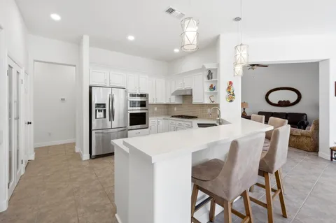 a kitchen with stainless steel appliances a refrigerator a stove a sink a dining table and chairs with wooden floor