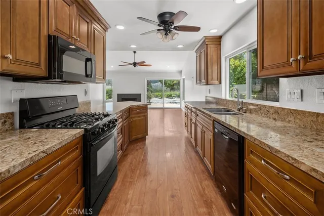 a kitchen with stainless steel appliances granite countertop wooden cabinets stove a sink and dishwasher a oven with wooden floor