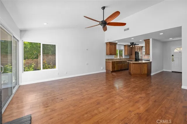 a living room with stainless steel appliances wooden floors and kitchen view
