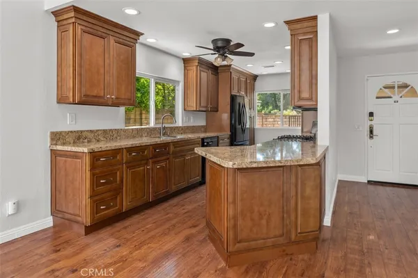 a kitchen with granite countertop a sink cabinets and wooden floor