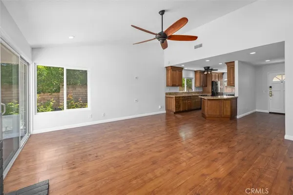 a living room with stainless steel appliances wooden floors and kitchen view