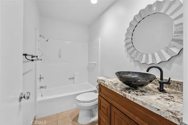 a bathroom with a granite countertop sink a toilet and bathtub