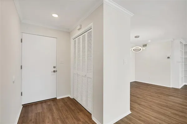 a view of empty room with wooden floor and kitchen view