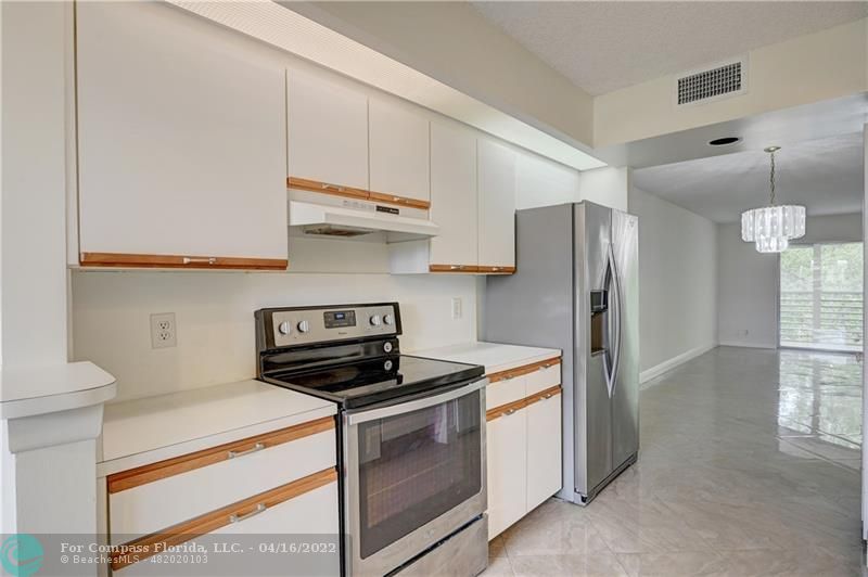 a kitchen with stainless steel appliances a refrigerator a stove and white cabinets