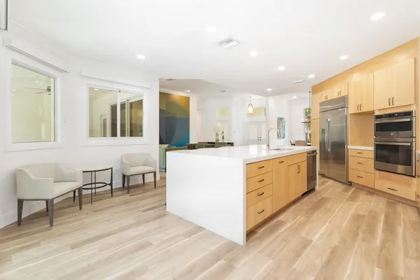 a large white kitchen with wooden floor and a sink